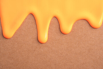 Orange liquid drops of paint color flow down on craft paper. Abstract art. Orange paint dripping on...