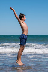 Happy boy performs pirouettes and big jumps on the seashore during his summer vacation on the Atlantic Coast, Las Grutas, Rio Negro, Argentina. © buenaventura13