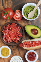 Completo Italian Chilean Vertical: Aerial view of hot dog bun with longaniza sausage, tomato, avocado and mayonnaise on wooden table. Typical Chilean food concept