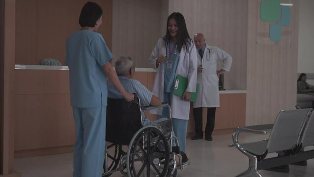 The Nurse Is Pushing Wheel Chair For The Elderly Male Patient Talk To The Female Doctor