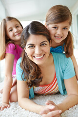 Relaxing with her two beautiful daughters. A pretty young mother having fun with her two cute daughters on the living room floor.