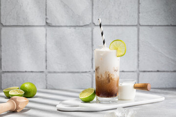 Trendy authentic dirty soda cocktail with cola, lime juice and cream in the kitchen table