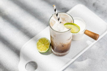 Trendy authentic dirty soda cocktail with cola, lime juice and cream in the kitchen table, top view