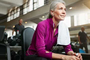 Catching a breather during exercise will make for better fitness. Portrait of a happy senior woman taking a break from her workout at the gym.