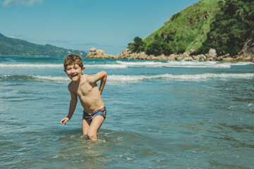 Fototapeta premium Menino brincando no mar da praia
