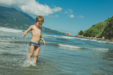 Menino brincando no mar da praia