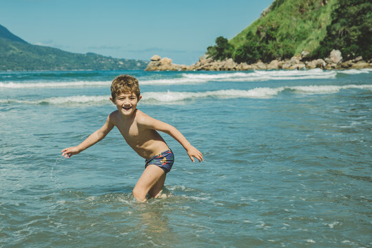 Menino brincando no mar da praia