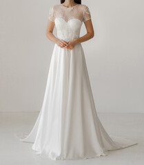 Front view of beautiful bride in the white wedding dress decorated with floral lace. Gorgeous short sleeves wedding dress decorated with lace