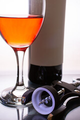 A glass of red wine, a bottle and a corkscrew