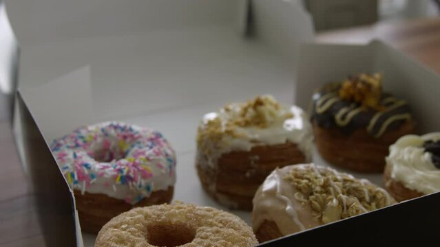 Womans hand places a fresh donut back in the box - resisting temptation