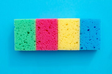 sponges of different colors for washing dishes, cleaning the house isolated on blue. Multicolored sponges for cleaning.  and dishwashing