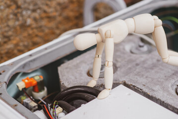 washing machine repair concept. A human figurine looks at the electrical circuits of a dismantled stylish car.
