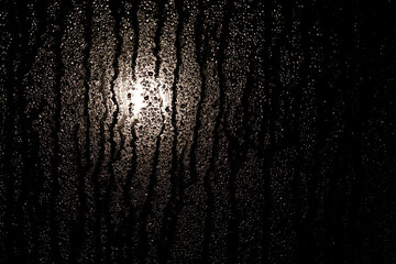 Szyba okienna w strugach deszczu w nocy ze światłem księżyca w tle © RAWIT