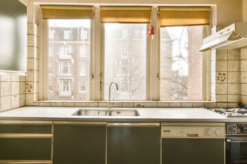 a kitchen with a sink and stove in it's corner, looking out to the street from behind an open window