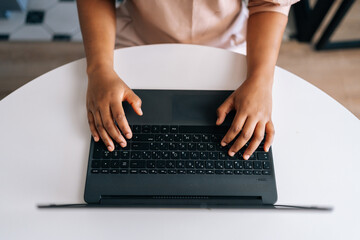 Closeup top view of unrecognizable African female student typing on notebook keyboard studying working online. Close up of black businesswoman typing on laptop computer at desk from remote home office