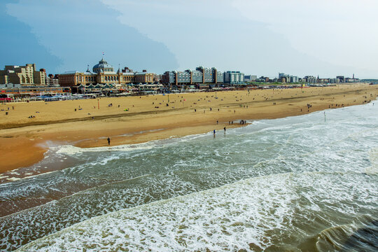 surf in The Hague: people walk along the coast and wet their feet in the water in distance