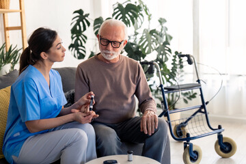 Senior man in retirement looking at his hand while nurse is poking his finger with needle pen to...