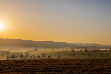Colourful sunrise on a summer morning with a little fog on the ground and spectacular views over the Dutch hillside near the village of Kuttingen