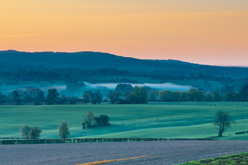 Colourful sunrise on a summer morning with a little fog on the ground and spectacular views over...