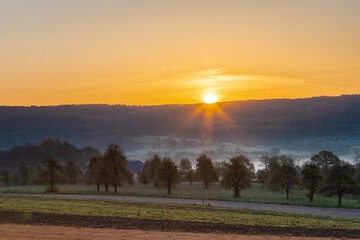 Fototapeta premium Colourful sunrise on a summer morning with a little fog on the ground and spectacular views over the Dutch hillside near the village of Kuttingen