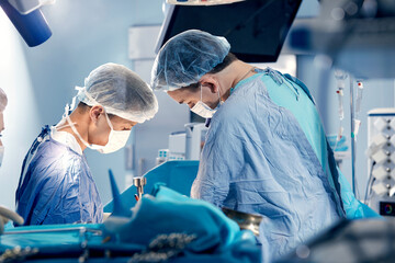 The team of surgeons in the operating room bent over the patient, complex surgical operation,...