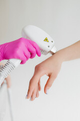 A beauty cosmetologist girl holds a device for laser hair removal (epilator) before starting the procedure in a beauty salon, close-up hand, epilation, depilation