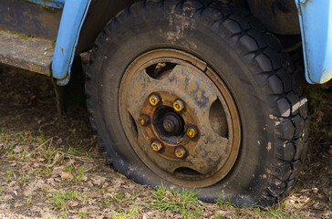 Fototapeta na wymiar A flat tire of an old fragment of a rusty abandoned broken truck.
