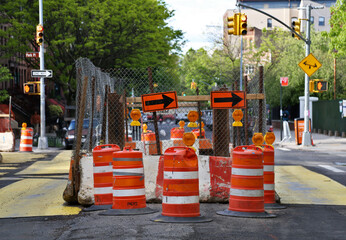 road work on a city street intersection (orange cones, bollards, barricades) arrows traffic light...