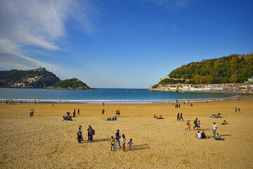 Obraz premium PLAYA DE ARENA CON GENTE EN UN DÍA SOLEADO EN SAN SEBASTIÁN, ESPAÑA.