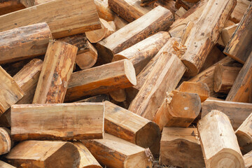 A pile of chopped wood for a fire as a background. Chopped tree trunks are thrown in a chaotic order on top of each other in close-up.
