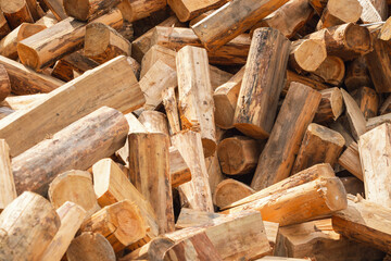 A pile of chopped wood for a fire as a background. Chopped tree trunks are thrown in a chaotic order on top of each other in close-up.