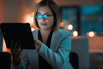 Online no matter the time. a businesswoman using a digital tablet during a late night at work.