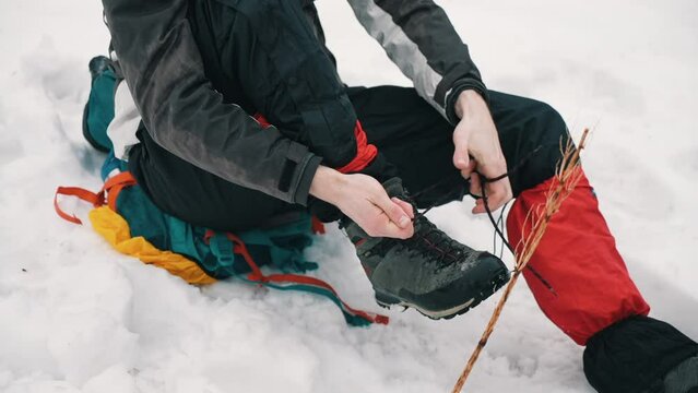 CARPATHIANS, HOVERLA, UKRAINE. Tourist man climbing a mountain tying shoelaces, close-up of shoes, began to rest and catch his breath, resting in the mountains, man in mountain gear. Difficult ascent