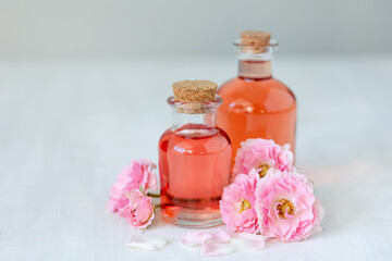 Fototapeta na wymiar Concept of perfume with pure natural organic rose ingredient, essential oils. Glass bottles with flower herbal extract and elixir. Perfumery cosmetic toilet water fragrance, cream, skin care product