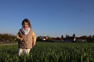 Naklejka na ściany i meble Happy little girl walking in the meadow 