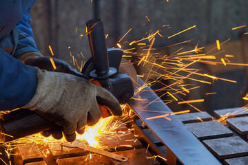 As master metal worker grinds metal on grinder there is spark in factory he works metalwork place