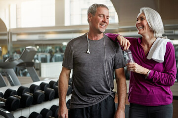 Marry someone that makes you laugh and keeps you fit. a senior married couple laughing and taking a break from their workout at the gym.