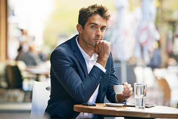 Time to do business...but first, coffee. a young businessman having coffee at a sidewalk cafe.