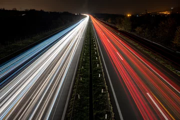 Foto op Plexiglas Snelweg bij nacht Cars light trails on a straight highway at sunset. Night traffic trails, Motion blur, Night city road with traffic headlight motion. 