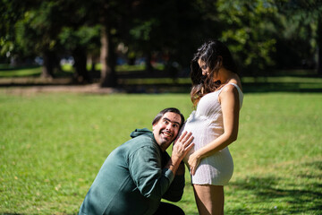 Man listening to his pregnant wife's tummy and smiling