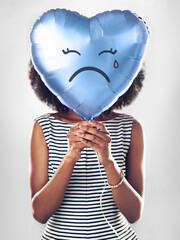 Im feeling a bit blue. a young woman holding up a heart shaped balloon.