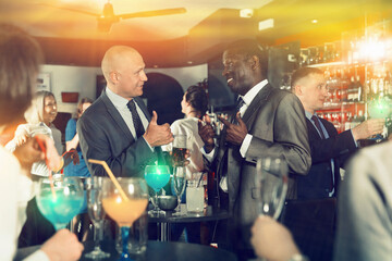 Portrait of African and Caucasian men having fun and talking on a corporate party