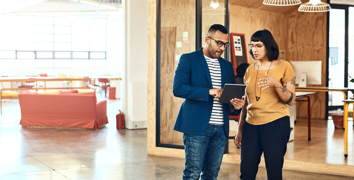 Technology enhances the way they work. two designers working on a digital tablet together in an office. - Powered by Adobe