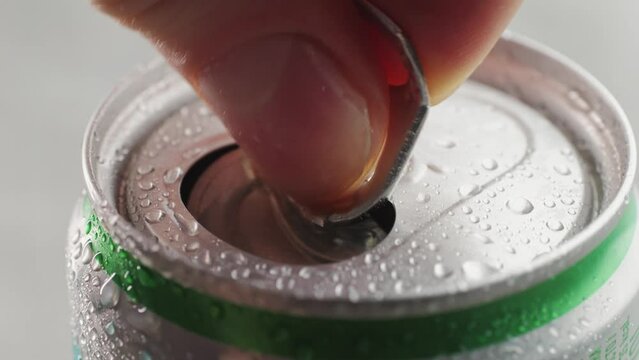 Opening soda or beer can, macro close up of can pull tab opening, watering refreshment, hand open lemonade or juice.