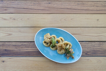 Isolated blue plate of breaded calamari rings, typically known by 
