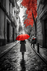 Red umbrella in hand of woman walking on a colorless street. AI generative - obrazy, fototapety, plakaty