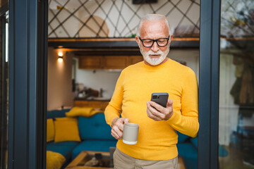 Senior Man Hold cup of coffee and Mobile Phone on Balcony