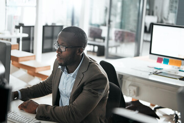 Success is one click away. a young businessman working on his computer at his desk.