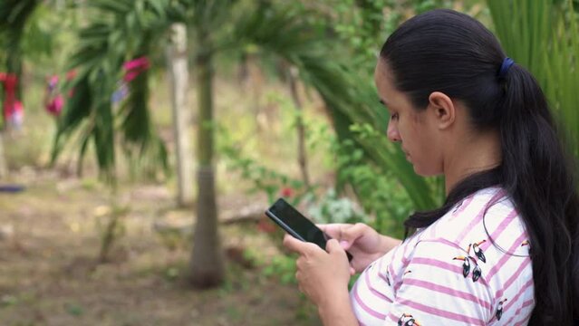 Escribiendo en la naturaleza: mujer en un campo escribiendo en su celular