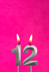 Candle 12 with flame - Silver anniversary candle on a fuchsia background